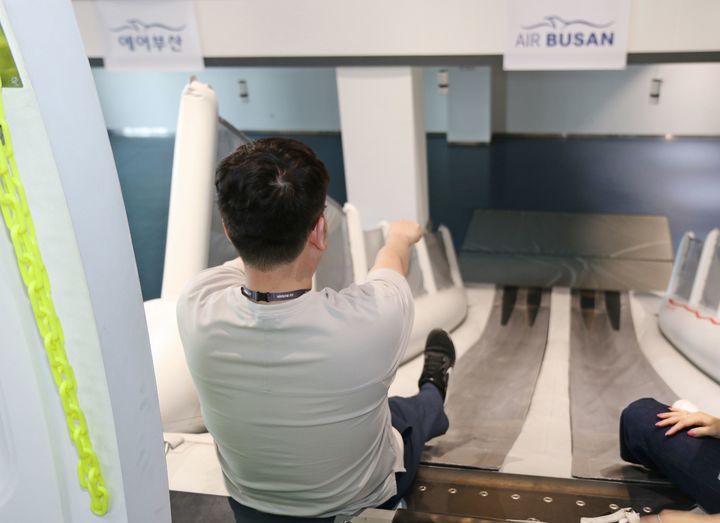 [부산=뉴시스] 에어부산 임직원이 사옥 훈련시설에서 비상탈출 슬라이드 탑승 실습을 하고 있다. (사진=에어부산 제공) 2025.06.19. photo@newsis.com *재판매 및 DB 금지