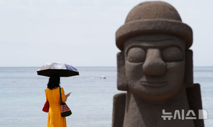 [제주=뉴시스] 우장호 기자 = 19일 오후 제주시 이호해수욕장에서 한 관광객이 양산으로 뜨거운 태양을 피하고 있다.올해 조기 개장하는 도내 해수욕장은 함덕·이호·협재·금능·월정·곽지를 비롯해 삼양·김녕·화순·표선 등 총 10곳(24일)이며, 신양과 중문 해수욕장은 26일과 30일 각각 개장한다. 2025.06.19. woo1223@newsis.com