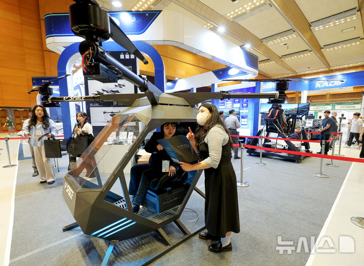 [서울=뉴시스] 김진아 기자 = 19일 서울 강남구 코엑스에서 열린 2025 국토교통기술교류회 브이스페이스 부스에서 관계자가 완전자율주행 기능이 탑재된 1인승 UAM에 대해 설명하고 있다. 2025.06.19. bluesoda@newsis.com