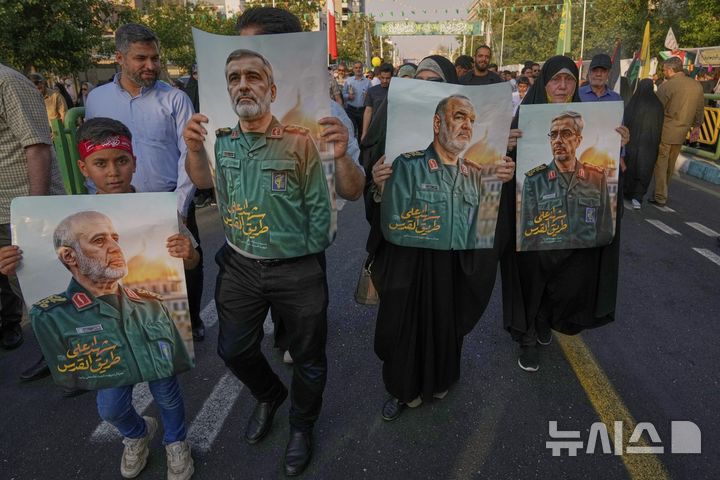 [테헤란=AP/뉴시스] 이란 수도 테헤란에서 지난 14일(현지 시간) 시위대가 이스라엘 공습으로 사망한 최고 사령관의 사진을 들고 행진하고 있다. 이스라엘과 일주일 넘게 무력 충돌을 이어가는 이란이 외부적으론 큰 타격을 입었지만, 내부 결속은 강화되고 있다는 주장이 나왔다. 2025.06.20.