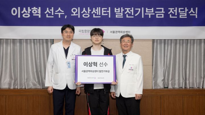 [서울=뉴시스] 이상혁 선수의 기부금 전달 장면. 윤석화 서울권역외상센터장(왼쪽), 서길준 국립중앙의료원 원장(오른쪽).(사진=국립중앙의료원 공식 블로그 갈무리) *재판매 및 DB 금지