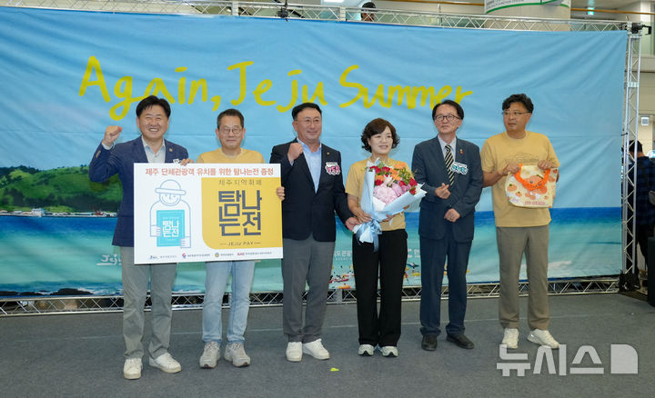 [제주=뉴시스] 제주도는 21일 오후 제주국제공항 1층에서 ‘가성비에 반하고, 가심비에 머무는 제주’를 주제로 관광객 환영행사를 열었다. 사진은 단체관광객에 여행지원금 '탐나는전'과 꽃다발, 기념품을 전달하는 모습. (사진=제주도 제공) 2025.06.21. photo@newsis.com *재판매 및 DB 금지