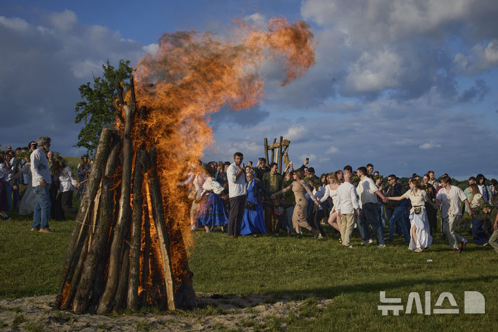 [피로히우(우크라이나)= AP/뉴시스] 우크라이나의 전통적 하지 축제 '이바나 쿠팔라'가 열린 6월 21일 저녁 키이우 교외의 국립민속건축박물관 뜰에서 사람들이 전통의상을 입고 함께 춤추고 있다. 2025.06.22. 