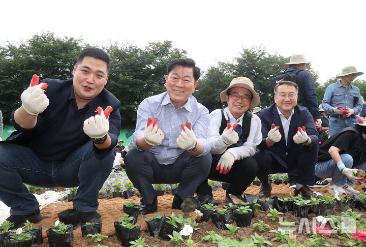 [광명=뉴시스]박승원 광명시장(사진 왼쪽 두 번째)이 21일 정원추진단과 함께 안양천 징검다리 앞 초화원에 정원을 조성하며 기념사진을 촬영하고 있다.(사진=광명시 제공)2025.06.22.photo@newsis.com