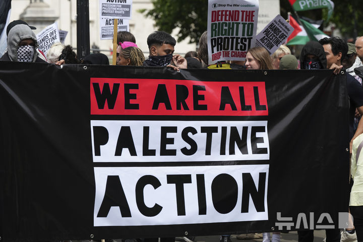 [런던=AP/뉴시스]2025년 6월23일 영국 런던에서 친팔레스타인 행동단체 '팔레스타인 행동'의 테러 단체 지정에 항의하는 시위대가 "우리는 모두 팔레스타인 행동'이다"이라고 쓰인 현수막을 들고 있다. 영국 정부가 시위 단체인 '팔레스타인 행동'을 테러 조직으로 지정한 것은 불법이라고 영국 고등법원이 13일 판결했다. 2026.02.13.