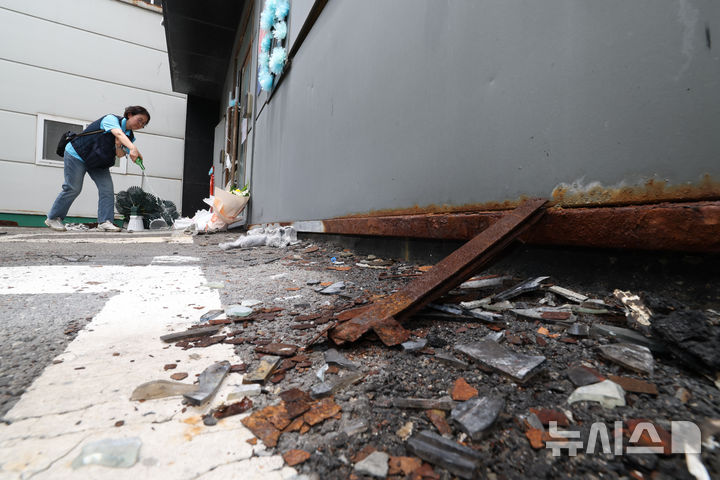 [화성=뉴시스] 김종택 기자 = '아리셀 참사 1주기 현장 추모 위령제'에서 아리셀 중대재해 참사 대책위원회 관계자가 화재 건물 앞에 술을 뿌리고 있다. (공동취재) 2025.06.24. photo@newsis.com