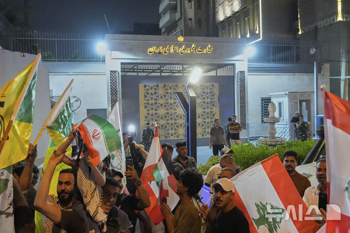 [바그다드=AP/뉴시스] 지난 6월 24일 이라크 바그다드에서 이란 국기를 든 시위대가 이라크 주재 이란 대사관 앞에 모여 이란과 이스라엘의 휴전을 환영하고 있다. 바그다드에서는 7월 27일 회의중인 정부 청사에 무장군인들이 난입해 보안 경찰 1명과 민간인 1명이 피살당하고 14명이 체포되었다. 2025.07.28.