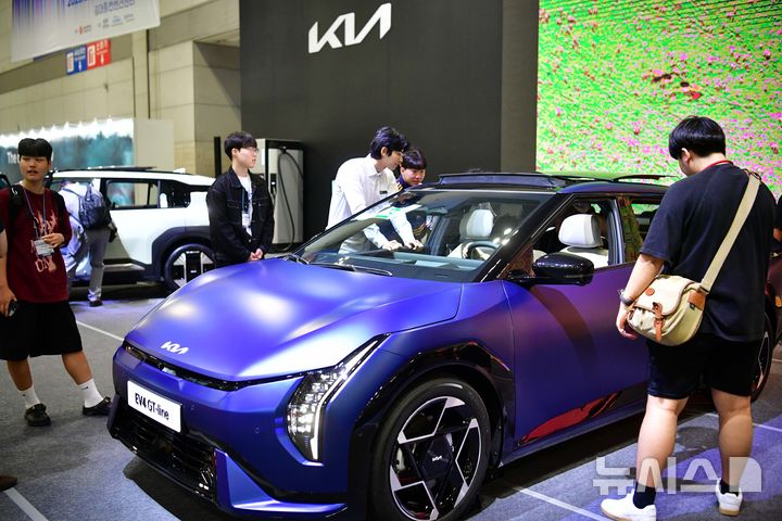 [광주=뉴시스] 이현행 기자 = 25일 오후 광주 서구 김대중컨벤션센터에서 열린 2025 광주미래산업엑스포에서 관람객들이 KIA 부스 EV4 GT-Line 모델에 대한 설명을 듣고 있다. 2025.06.25 lhh@newsis.com