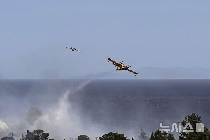 [AP/뉴시스] 26일 그리스 아테네 남부 팔라이아 포카이야 해변에서 소방 헬리가 물을 뿌리고 있다