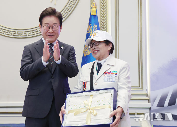 [서울=뉴시스] 최진석 기자 = 이재명 대통령이 27일 청와대 영빈관에서 열린 '호국보훈의 달, 대통령의 초대' 행사에서 특별초청 대상자인 6·25전쟁 참전유공자 이춘자 참전용사에게 광목이불 선물을 전달 후 박수치고 있다. (대통령실통신사진기자단) 2025.06.27. myjs@newsis.com
