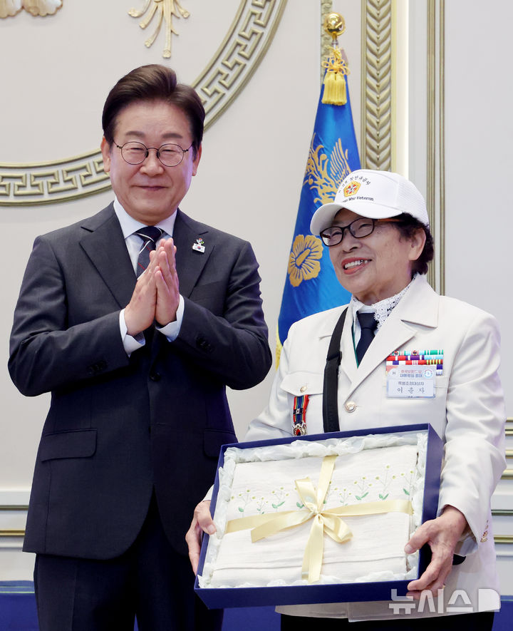 [서울=뉴시스] 최진석 기자 = 이재명 대통령이 27일 청와대 영빈관에서 열린 '호국보훈의 달, 대통령의 초대' 행사에서 특별초청 대상자인 6·25전쟁 참전유공자 이춘자 참전용사에게 광목이불 선물을 전달 후 박수치고 있다. (대통령실통신사진기자단) 2025.06.27. myjs@newsis.com