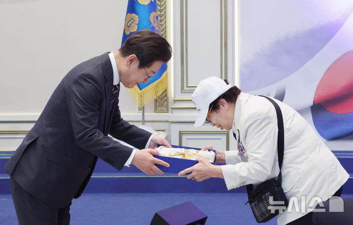 [서울=뉴시스] 최진석 기자 = 이재명 대통령이 27일 청와대 영빈관에서 열린 '호국보훈의 달, 대통령의 초대' 행사에서 특별초청 대상자인 6·25전쟁 참전유공자 이춘자 참전용사에게 광목이불 선물을 전달하고 있다. (대통령실통신사진기자단) 2025.06.27. myjs@newsis.com
