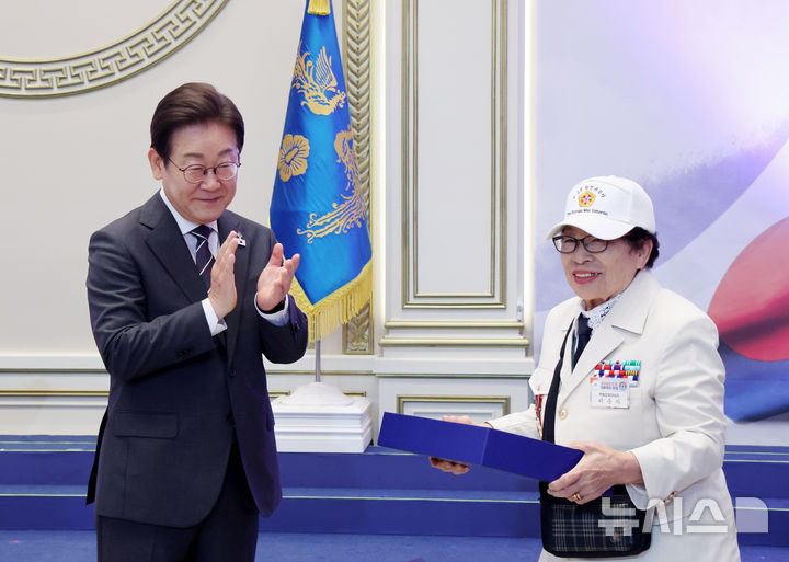 [서울=뉴시스] 최진석 기자 = 이재명 대통령이 27일 청와대 영빈관에서 열린 '호국보훈의 달, 대통령의 초대' 행사에서 특별초청 대상자인 6·25전쟁 참전유공자 이춘자 참전용사에게 광목이불 선물을 전달 후 박수치고 있다. (대통령실통신사진기자단) 2025.06.27. myjs@newsis.com
