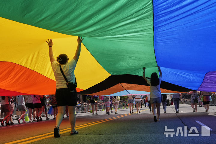 [내슈빌=AP/뉴시스] 28일(현지 시간) 미 테네시주 내슈빌에서 열린 연례 LGBTQ+ 내슈빌 프라이드 행진 참가자들이 대형 무지개 깃발을 들고 있다. 2025.06.29.