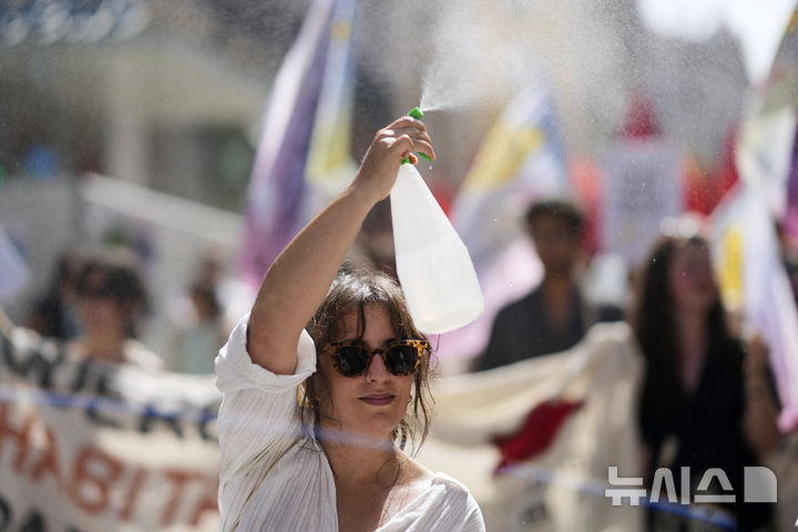 [AP/뉴시스] 28일 포르투갈 리스본에서 주택 위기 시위에 참가한 여성이 더위에 스프레이로 물을 뿌리고 있다