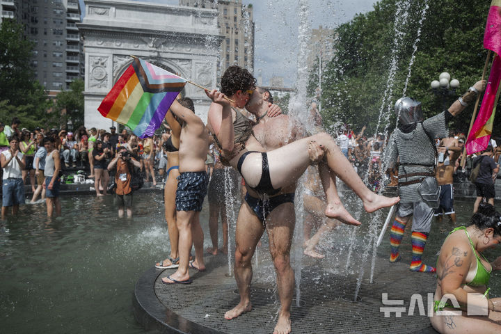 [뉴욕=AP/뉴시스] 29일(현지 시간) 미 뉴욕주 뉴욕에서 열린 프라이드 퍼레이드를 마친 연인이 워싱턴 스퀘어 파크에서 분수를 맞으며 입 맞춤하고 있다. 매년 6월은 '세계 성소수자 프라이드의 달'로 세계 곳곳에서 기념행사가 열린다. 2025.06.30.