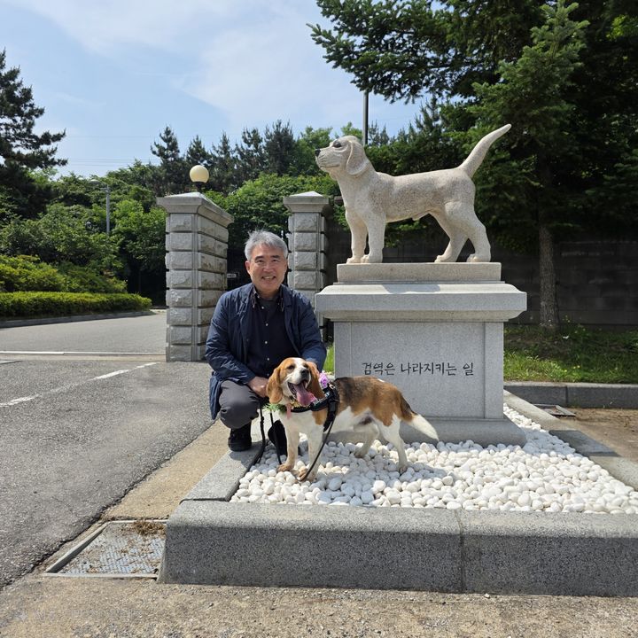 [세종=뉴시스] 농림축산검역본부 은퇴 검역탐지견 '알파'와 입양자가 탐지견 센터 동상 앞에서 기념 촬영을 하고 있다. (사진=검역본부 제공) *재판매 및 DB 금지