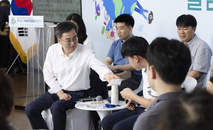 [수원=뉴시스] 30일 시흥에코센터에서 열린 '경기도 기후도민총회' 출범식에 참석한 김동연 지사가 학생 참가자에게 땀을 닦으라며 자신의 손수건을 건네고 있다. (사진=경기도 제공) 2025.06.30. photo@newsis.com *재판매 및 DB 금지