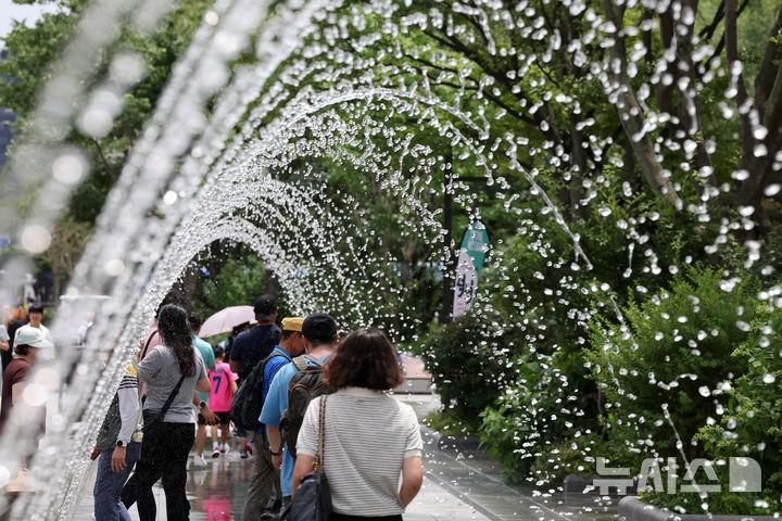 [서울=뉴시스] 배훈식 기자 = 서울에 올해 첫 폭염주의보가 발효된 30일 오후 서울 종로구 광화문광장에서 관광객들이 바닥분수 터널을 걸으며 더위를 식히고 있다. 2025.06.30. dahora83@newsis.com