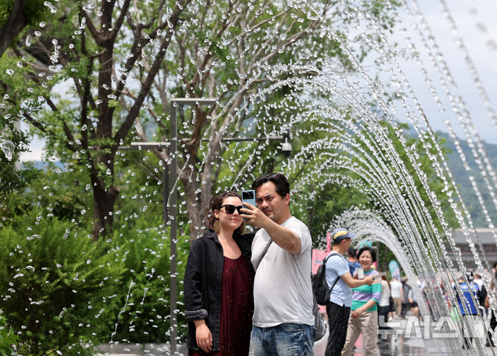 [서울=뉴시스] 배훈식 기자 = 서울에 올해 첫 폭염주의보가 발효된 30일 오후 서울 종로구 광화문광장에서 관광객들이 바닥분수 터널을 걸으며 더위를 식히고 있다. 2025.06.30. dahora83@newsis.com