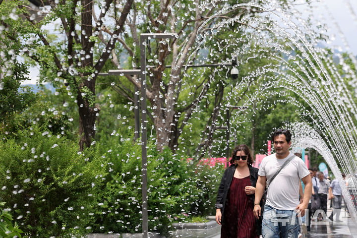 [서울=뉴시스] 배훈식 기자 = 서울에 올해 첫 폭염주의보가 발효된 30일 오후 서울 종로구 광화문광장에서 관광객들이 바닥분수 터널을 걸으며 더위를 식히고 있다. 2025.06.30. dahora83@newsis.com