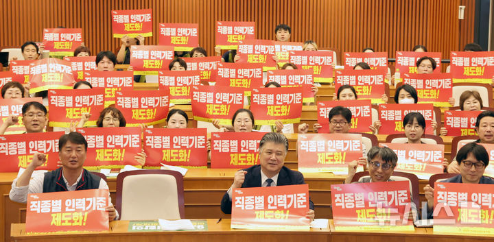 [서울=뉴시스] 김금보 기자 = 민주노총 전국보건의료산업노동조합 조합원들과 토론회 패널들이 30일 서울 여의도 국회박물관에서 열린 '이재명 정부 공약 및 정책협약 이행 과제 국회토론회, 보건의료 위기와 갈등의 시대! 이재명 정부 출범 100일 내 해결해야 할 최우선 과제는 무엇인가?'에서 직종별 인력기준 제도화와 9.2 노정합의 이행협의체 논의재개를 요구하는 피켓을 들고 구호를 외치고 있다. 2025.06.30. kgb@newsis.com