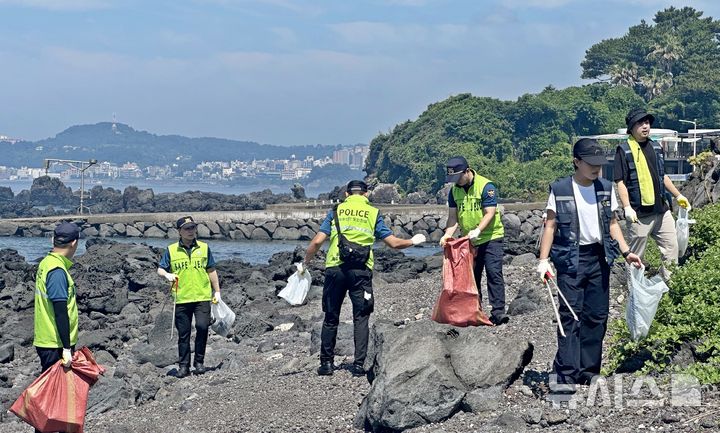 [제주=뉴시스] 제주경찰청 제주해안경비단이 2일 서귀포시 보목동 구두미포구 일대에서 장애인지원센터 등과 해안 환경정화활동을 하고 있다. (사진=제주해안경비단 제공) 2025.07.02. photo@newsis.com