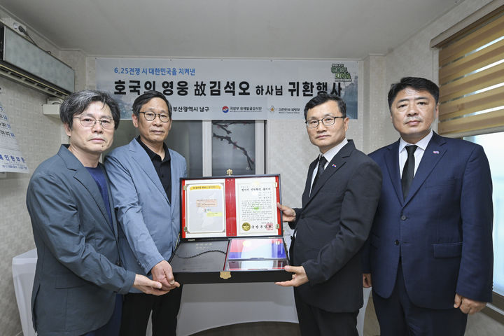 [서울=뉴시스]호국의 얼' 함을 전달하고 기념사진을 촬영하고 있는 고 김석오 하사의 유가족과 이근원 국방부유해발굴감식단장(왼쪽에서 세 번째), 오은택 부산광역시 남구청장(맨 오른쪽). (사진=국유단 제공) 2025.07.02. *재판매 및 DB 금지