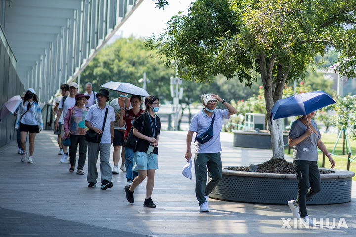 [항저우(중 저장성)=AP/뉴시스]오렌지색 폭염 경보가 발령된 지난 4일 중국 저장(浙江)성 항저우(杭州)를 찾은 관광객들이 우산 등으로 해를 가리고 있다. 중국 동북부 지역 기온이 40도를 넘어서면서 에어컨이 설치되지 않은 무더운 기숙사 생활을 견디지 못하고 야외에 텐트를 치고 생활하거나 방 안보다 조금 시원한 복도, 슈퍼마켓 등에서 야영하는 대학생들이 크게 늘었으며, 일부 부유한 학생은 호텔에 투숙하기도 한다고 BBC기 9일(현지시각) 보도했다. 2025.07.10.