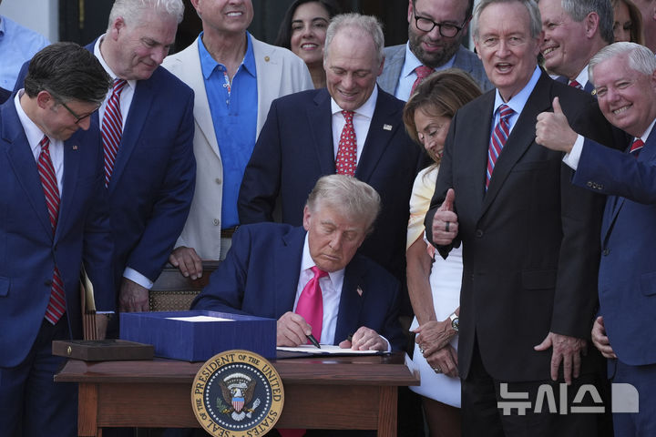 [워싱턴=AP/뉴시스]도널드 트럼프 미 대통령이 4일(현지시각) 백악관에서 의원들에게 둘러싸인 채 감세 및 지출 을 규정하는 메가법안에 서명하고 있다. 2025.7.5. 