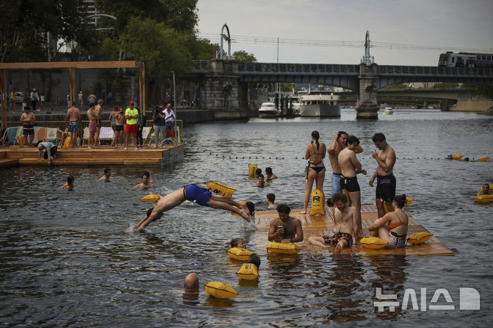 [파리=AP/뉴시스] 5일(현지 시간) 프랑스 파리 센 강에서 시민들이 수영을 하고 있다. 센 강은 100여 년 만에 공공 수영 공간으로 개방됐다. 마리 수로, 베르시 강변, 그르넬 항구 근처 등 세 곳이 야외 수영 구역으로 지정됐으며 오는 8월 31일까지 무료로 개방된다. 탈의실, 샤워 시설, 파라솔, 비치체어 등이 갖춰졌다. 2025.07.07.