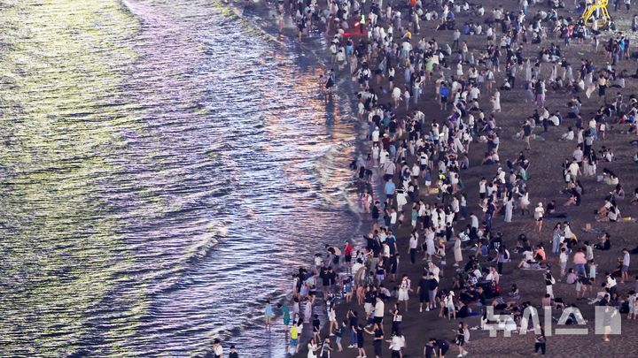 [부산=뉴시스] 하경민 기자 = 폭염특보와 열대야 현상으로 인해 밤낮으로 푹푹 찌는 더위가 이어진 5일 밤 부산 수영구 광안리해수욕장에서 시민과 관광객들이 더위를 식히고 있다. 2025.07.06. yulnetphoto@newsis.com