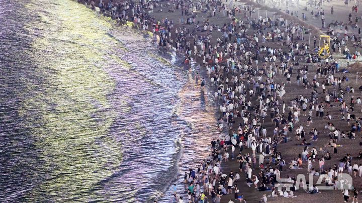 [부산=뉴시스] 하경민 기자 = 폭염특보와 열대야 현상으로 인해 밤낮으로 푹푹 찌는 더위가 이어진 5일 밤 부산 수영구 광안리해수욕장에서 시민과 관광객들이 더위를 식히고 있다. 2025.07.06. yulnetphoto@newsis.com