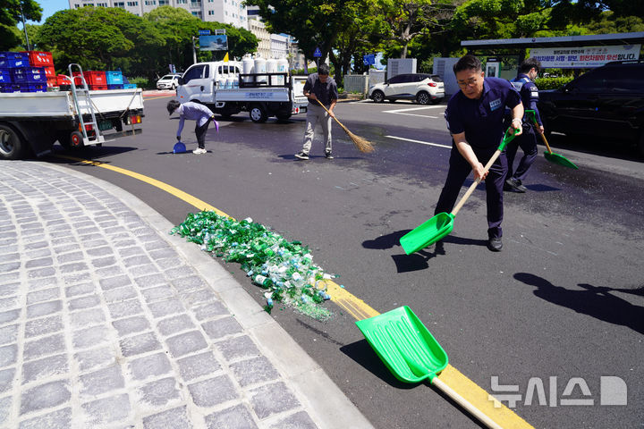 [제주=뉴시스] 7일 오전 10시50분께 제주시 연동 신제주로터리에서 청원경찰들이 도로에 흩어진 주류 박스와 깨진 소주병들을 수거하고 있다. (사진=제주도 제공) 2025.07.07. photo@newsis.com