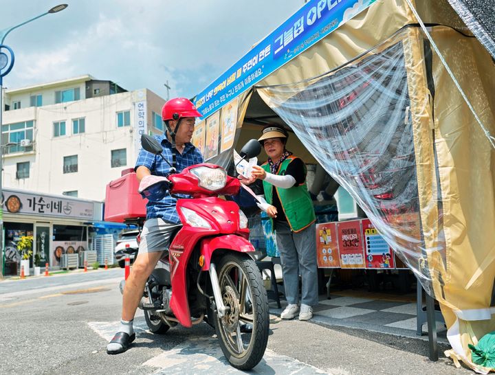 [광주=뉴시스] 박기웅 기자 = 광주 광산구 송정1동 주민자치회, 자율방재단 등 관계자들이 지난 7일 이동식 그늘집을 설치, 배달원에게 얼음 생수를 건네고 있다. (사진 = 광주 광산구 제공) 2025.07.08. photo@newsis.com *재판매 및 DB 금지