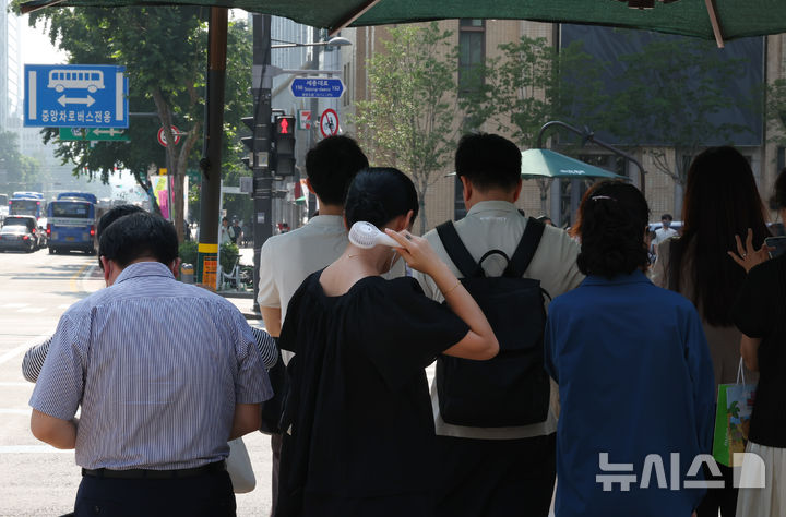 [서울=뉴시스] 최진석 기자 = 폭염이 이어지고 있는 8일 서울 세종대로사거리 인근에서 한 시민이 그늘막 아래서 손 선풍기를 틀고 더위를 식히고 있다. 2025.07.08. myjs@newsis.com