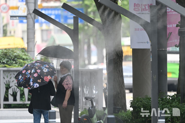 [광주=뉴시스] 이영주 기자 = 광주지역에 폭염특보가 이어지고 있는 8일 오후 광주 동구 금남로에서 시민들이 양산을 쓴 채 쿨링포그가 뿜어내는 물안개를 맞고 있다. 2025.07.08. leeyj2578@newsis.com