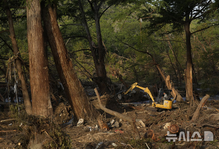 <font style="vertical-align: inherit;"><font style="vertical-align: inherit;"></font></font><font style="vertical-align: inherit;"><font style="vertical-align: inherit;">[텍사스=AP/뉴시스] 8일(현지 시간) 미국 텍사스주 과달루페 강 인근 홍수 피해 지역에서 자원봉사자가 굴삭기를 이용해 나뭇가지 등 잔해를 치우고 있다. 2025.07.09.</font></font>