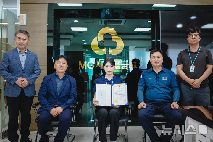 [창원=뉴시스]9일 경남 창원특례시 진해구 새진해새마을금고 입구에서 이유빈(가운데) 계장이 진해경찰서장으로부터 보이스피싱 예방 공로로 감사장을 받은 후 기념촬영하고 있다.(사진=새진해새마을금고 제공) 2025.07.09. photo@newsis.com