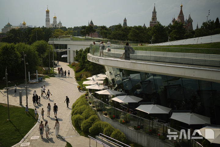 [모스크바=AP/뉴시스] 더운 날씨를 보인 9일(현지 시간) 러시아 모스크바의 크렘린궁 외곽에 위치한 자리야디예 공원에서 시민들이 이동하고 있다. 이날 기온은 32도까지 올랐다. 2025.07.11.