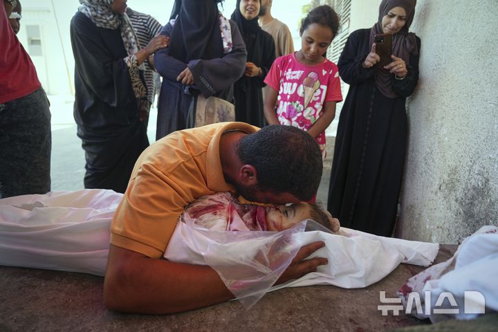 [가자지구=AP/뉴시스] 가자지구 데이르 알발라에 있는 '프로젝트 호프'가 운영하는 의료 클리닉 앞에서 영양 보충제를 기다리다 이스라엘의 공습으로 숨진 딸의 시신 앞에서 슬퍼하고 있다. 이번 공습으로 여성 두 명과 어린이 다섯 명을 포함해 총 10명이 숨졌다.