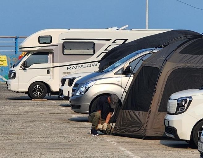 [서울=뉴시스] 경남 거제 흥남 해수욕장의 공영주차장에서 아스팔트에 드릴로 구멍을 뚫어 텐트를 고정하는 '민폐 캠핑족'이 출몰해 논란이 일고 있다. (사진 = 보배드림 캡처) 2025.07.10. *재판매 및 DB 금지