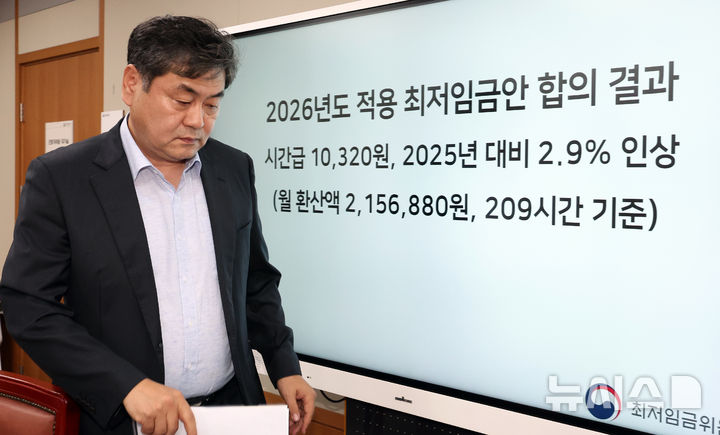 [세종=뉴시스] 강종민 기자 = 이인재 최저임금위원장이 10일 밤 세종시 정부세종청사에서 열린 최저임금위원회 제12차 전원회의를 마친 뒤 2026년도 적용 최저임금안 합의 결과 앞을 지나고 있다.  내년도 최저임금은 1만 320원으로 결정됐다. 2024.07.10. ppkjm@newsis.com