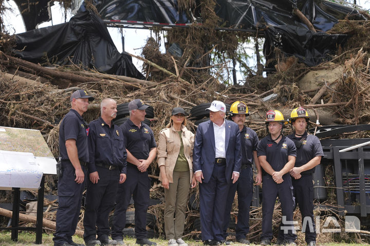 [커빌(텍사스주)=AP/뉴시스]도널드 트럼프 미국 대통령이 멜라니아 여사와 지난 11일(현지 시각) 미 텍사스주 커빌의 홍수 피해 지역을 방문해 수색대원 등과 기념촬영을 하고 있다. 이날 트럼프는 당국의 대응이 늦어져 피해가 커졌다고 질문하는 기자를 "사악한 사람"이라고 비난했다. 2025.07.17.