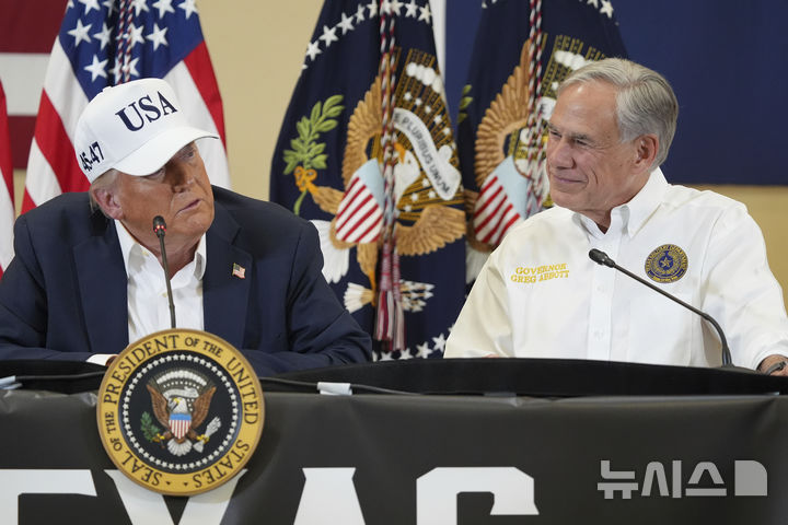 [커빌(텍사스주)=AP/뉴시스]도널드 트럼프 미국 대통령이 11일(현지 시간) 텍사스주 커빌의 힐 컨트리 청소년이벤트센터에서 간담회를 열고 발언하는 모습을 그레그 애벗 주지사가 지켜보고 있다. 2025.07.31.
