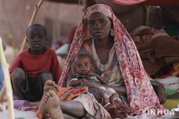 [ 엘파셰르( 수단)=신화/뉴시스] 수단의 북 다르푸르주 엘파셰르에 있는 난민 수용소에서 한 여성이 굶주린 채 아기를 안고 앉아있다.  유엔아동기금(유니세프)은 내전으로 인한 봉쇄로 이곳 주민의 생명이 위태롭다고 밝혔고 RSF군의 폭격으로 10월 11일에도 민간인 57명이 숨졌다. 2025. 10.12.  