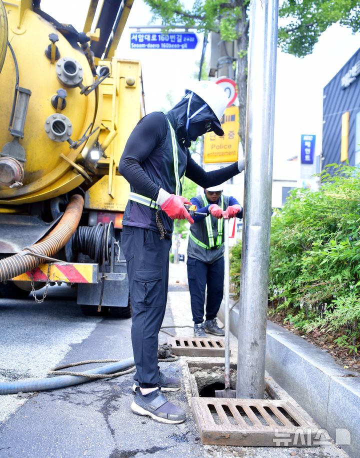 [광주=뉴시스] 이현행 기자=14일 오후 광주 북구 신안교 인근에서 북구청 관계자들이 17톤 다용도 복합 차량을 이용해 빗물받이 내 쓰레기 청소에 한창이다. 2025.07.14. lhh@newsis.com