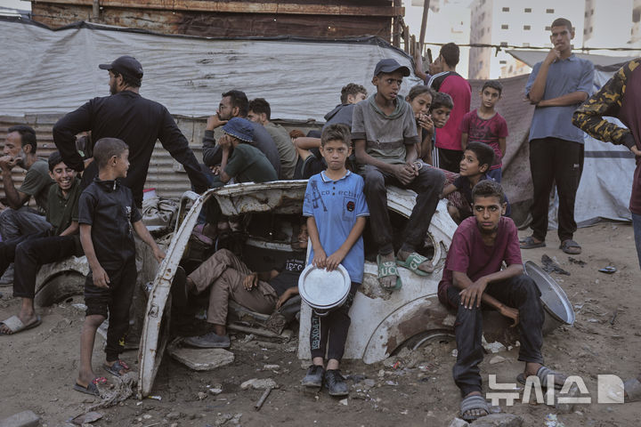 [가자시티=AP/뉴시스] 14일(현지 시간) 가자지구 가자시티 내 한 공동 급식소에서 음식을 받으려는 팔레스타인 어린이들이 식기를 들고 기다리고 있다. 2025.07.15.
