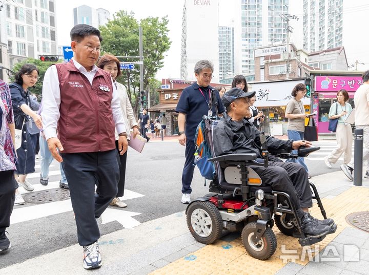 [서울=뉴시스]박강수 마포구청장이 휠체어를 탄 주민과 함께 새로 조성된 무장애길을 걷고 있다.