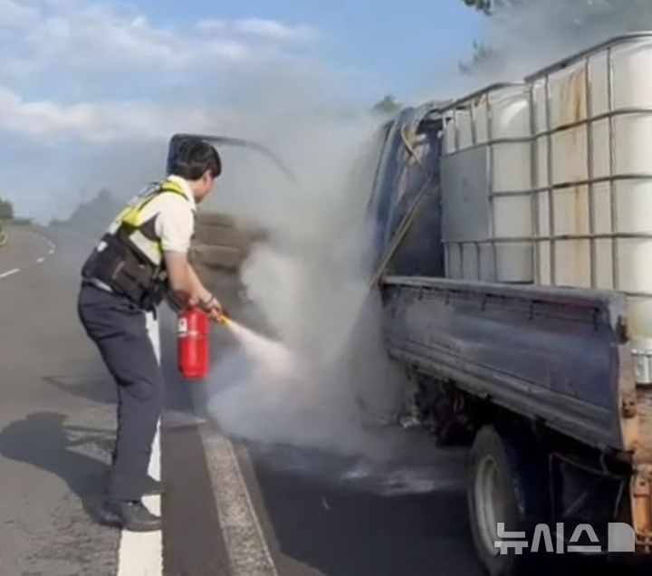 [제주=뉴시스] 제주자치경찰단 서귀포지역경찰대 소속 전재현 경장과 고도협 경장이 14일 오후 서귀포시 상창교차로 일대를 순찰하던 중 갓길에 세워진 1t트럭에서 불이 난 것을 보고 초기 진화를 벌이고 있다. (사진=제주자치경찰단 제공) 2025.07.15. photo@newsis.com 